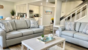 A modern living room with a grey sofa, a white coffee table, and a staircase leading to an upper level. - Inverness Villa on Golf Course with Pool & Tennis (Hilton Head Island)