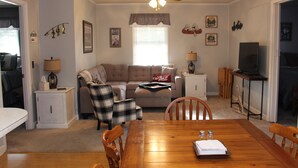 Una sala de estar acogedora con una mesa de comedor, un sofá, un sillón escocés y un televisor.