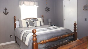 Un dormitorio con una cama de madera, una ventana con cortina, un reloj de pared y una puerta.