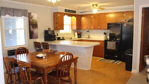Una cocina con armarios de madera, una isla central y una mesa de comedor con sillas.