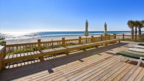 Une terrasse en bois avec des bancs donnant sur une plage.