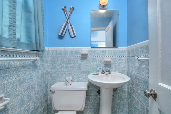 A bathroom with a toilet, sink, and blue tiled walls. - Rates REDUCED @ Twin Palms Cottage (Myrtle Beach)