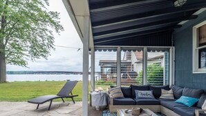 A covered outdoor seating area with a view of a lake and a bridge. - Lakefront Renovated 4BR w/ Dock, Kayaks, Walk to Bemus Point (Bemus Point)