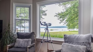 A room with two chairs, a telescope, and a view of a lake. - Lakefront Renovated 4BR w/ Dock, Kayaks, Walk to Bemus Point (Bemus Point)