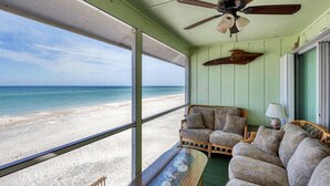 Ein Zimmer mit Blick auf den Strand, ausgestattet mit Deckenventilator, Korbmöbeln und einer Lampe.