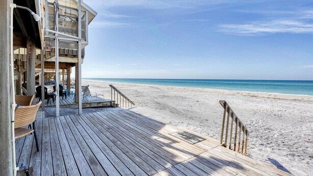 Eine Holzterrasse führt zu einem Strand mit freiem Blick auf das Meer.