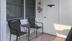 A door with a decorative crab and a bird, two chairs, and a patterned rug. - Cozy Beach Cottage in Island’s residential neighborhood! (Cape May)