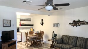 A living room with a television, sofa, coffee table, and dining area with chairs and a table. - Cozy Beach Cottage in Island’s residential neighborhood! (Cape May)