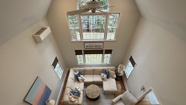 A spacious living room with a high ceiling, a large window, a ceiling fan, and a sign that reads "welcome to our beach house." - Osterville Gem with Central A/C and Walking Distance to Joshua’s Pond! (Osterville)