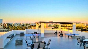 Enjoy breathtaking city views from this rooftop terrace, featuring comfortable seating and exercise bikes.