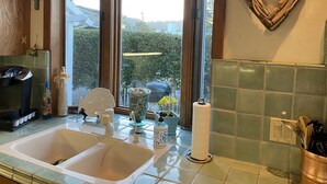 A kitchen with a double sink, a coffee maker, a vase with flowers, and a heart-shaped decoration on the wall.