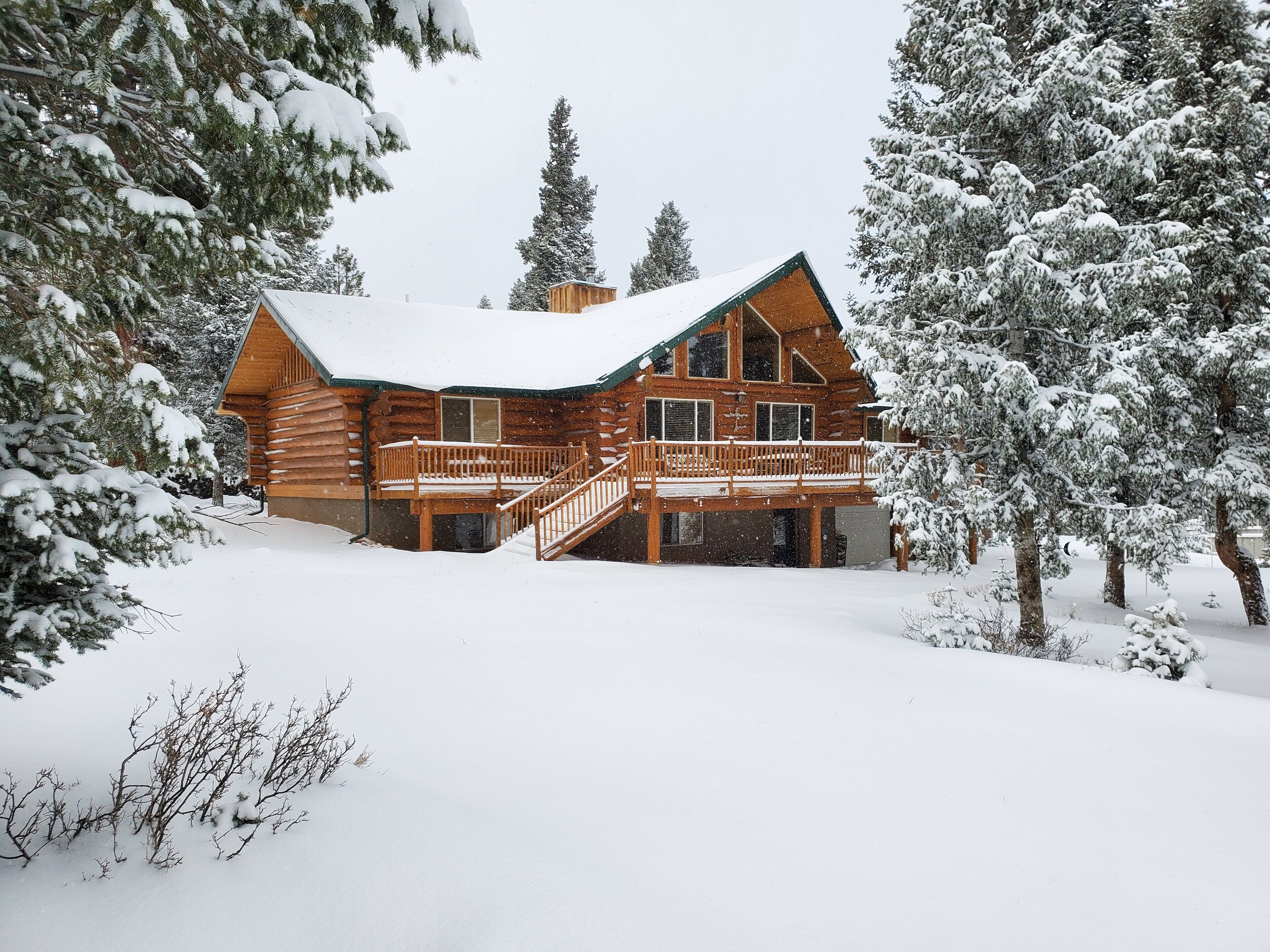 A log cabin with a wooden deck and a staircase leading to a second level.