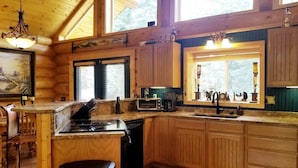 A wooden cabin kitchen with a central island, built-in microwave, and a window with decorative items. - PRICES REDUCED !  Luxury upscale cabin, quiet cul-de-sac, free Wi-Fi (Duck Creek Village)