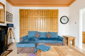 Een kamer met een houten garderobe, een blauwe bank, een klok en een statief.