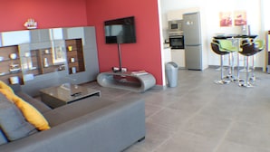 A modern living room with a grey sofa, a flat-screen TV mounted on the wall, and a glass coffee table. - Canyelles Mar Casa 1 (Roses)