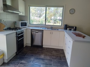 Kitchen features a stove, microwave, and dishwasher, with a sink and window above.