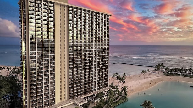 Un hotel moderno con piscina, playa y vista al océano.