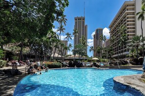 A swimming pool surrounded by palm trees and hotel buildings.