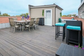 Une terrasse avec une table et des chaises, un petit abri de jardin et un espace salon extérieur.