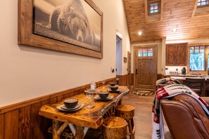 Un interior rústico de madera con un comedor que incluye una mesa larga, taburetes y un banco.