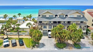 A beachfront hotel with multiple floors, a beach view, and a parking area with several cars. - 🐚 Silver Beach Retreat | Beachfront | FREE VIP Package | Beach Chair Service (Destin)