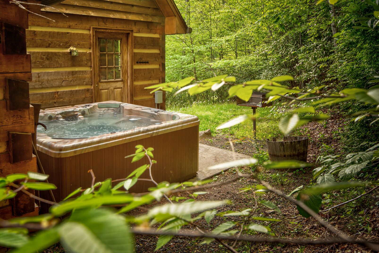 A wooden cabin with a hot tub and a lush garden.