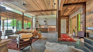 Un vaste espace de vie doté d’un haut plafond, de grandes fenêtres et d’un décor intérieur de style rustique.
