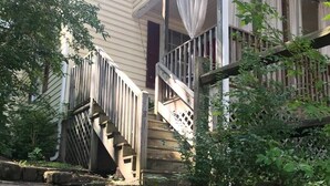 Een huis met twee verdiepingen, een veranda, stenen trappen en een houten omheining.