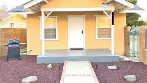 A small, single-story house with a white door and windows, a porch with a white railing, and a gravel driveway. - ♥ Charming entire house in the heart of Lancaster ♥ (Lancaster)