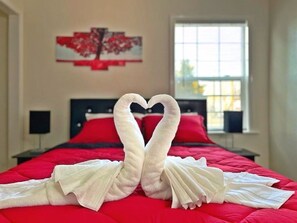 A hotel room with a red bedspread, a heart-shaped towel arrangement, and a painting on the wall. - ♥ Charming entire house in the heart of Lancaster ♥ (Lancaster)