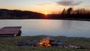 A lakeside view with a wooden dock and a campfire. - Winter celebration and solitude at Whispering Willows Farm (Dushore)