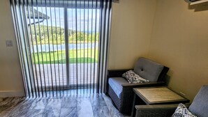 A room with a sliding glass door leading to a patio, a sofa with patterned cushions, and a small table. - Winter celebration and solitude at Whispering Willows Farm (Dushore)