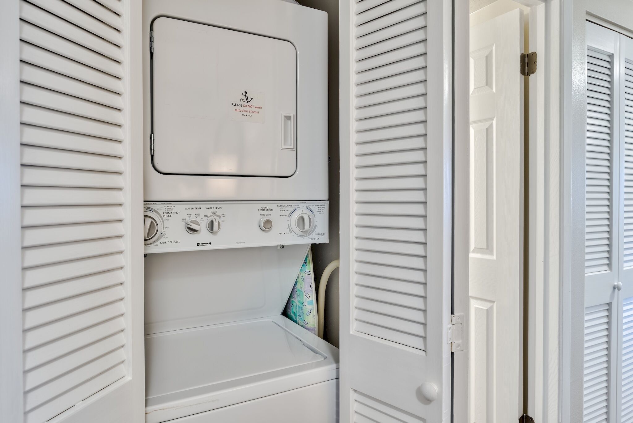 A white wall-mounted washer and dryer unit with control knobs and a message on the top.