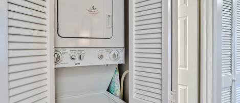 A white wall-mounted washer and dryer unit with control knobs and a message on the top.