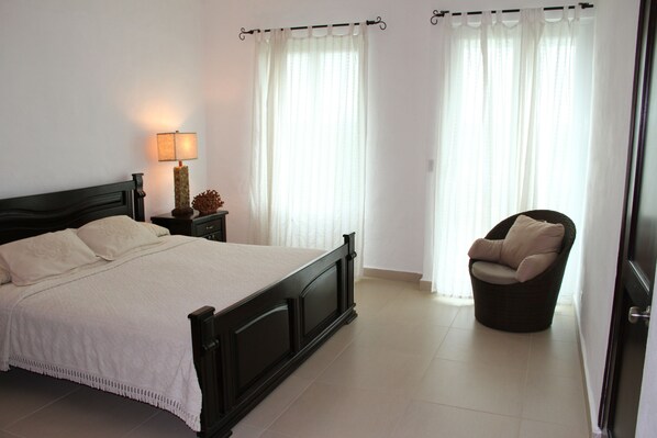 A bedroom with a bed, nightstand, lamp, and chair.