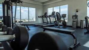 Una palestra con tapis roulant, una panca e attrezzi per sollevamento pesi.