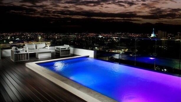 Una piscina a sfioro sul tetto con vista sulla città al crepuscolo.