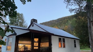 Ein kleines, eingeschossiges Haus mit Satteldach, einer Veranda und einer sichtbaren Treppe zum Eingang.