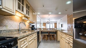 Une cuisine moderne dotée de plans de travail en granit, de meubles de couleur beige et d’un îlot central avec des tabourets de bar.