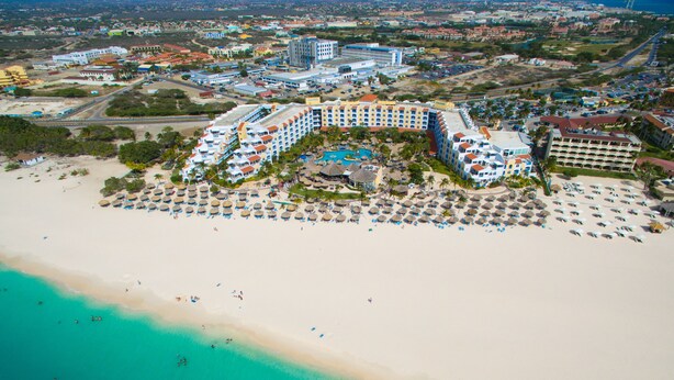 Un complexe hôtelier comprenant plusieurs bâtiments, une plage et un espace piscine.