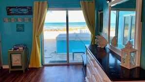Habitación con vista a la playa, un espejo grande y un mueble pequeño con un marco de fotos.