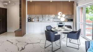 A modern kitchen with white cabinets, a marble countertop, and a round dining table with four chairs. - Holiday Mountain Residence by Interhome (Swieradow Zdroj)