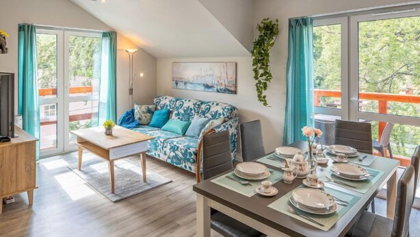 A modern living room with a sofa, dining table set for four, and a balcony with a view. - Holiday Mountain Residence by Interhome (Swieradow Zdroj)