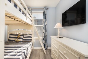 A bedroom with a bunk bed, a desk, a TV, and a window with blinds. - Sunset Island 33 Sunset Island Drive (Ocean City)