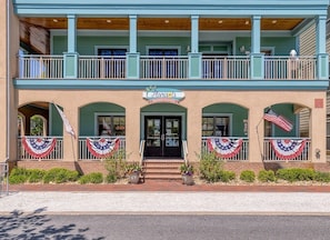 Un bâtiment à deux étages doté d’un balcon, d’une enseigne indiquant « Marie’s Market & Cafe » et de drapeaux américains à l’avant.