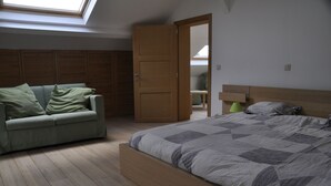 Une chambre à coucher avec un lit, un canapé, une armoire en bois et une lucarne.