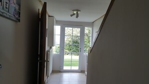 Un couloir avec une porte donnant sur un jardin.