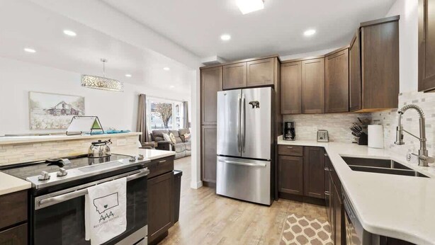 A modern kitchen with dark wood cabinets, stainless steel appliances, and a white countertop. - 63 Bar (Red Lodge)