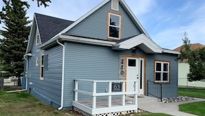 A single-story house with a front porch, a small deck, and a mailbox. - 63 Bar (Red Lodge)