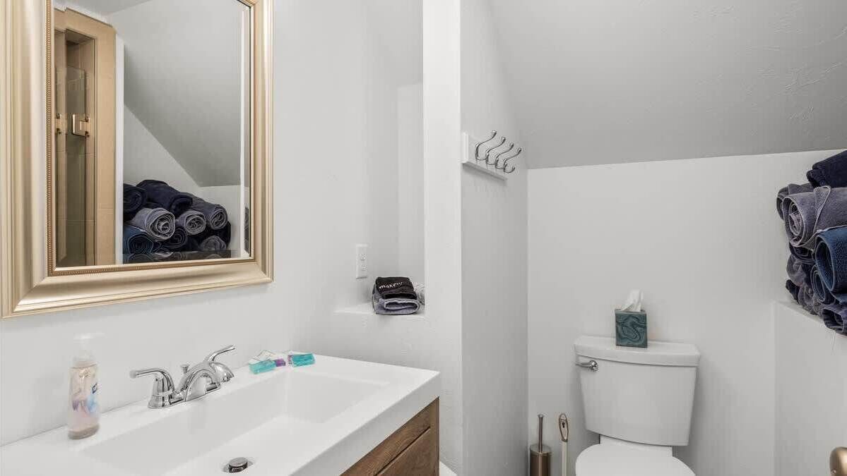 A modern bathroom with a white sink, a mirror, and a toilet.
